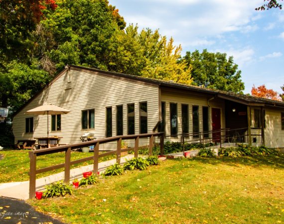 Back yard view with ramp, tan house, patio chairs.